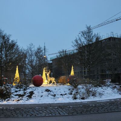 Foto: Ein Kreisverkehr mit leuchtender Weihnachtsdeko. Im Hintergrund eine große Baustelle.