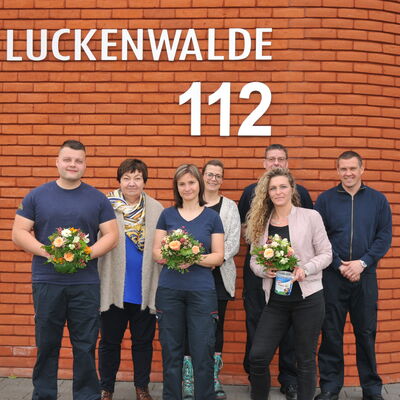 Foto: Mehrere Menschen vor einem roten Backsteingebäude.
