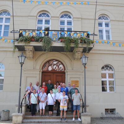 Foto: Eine Gruppe Menschen vor einem Gebäude, das mit blauen und gelben Wimpeln geschmückt ist.