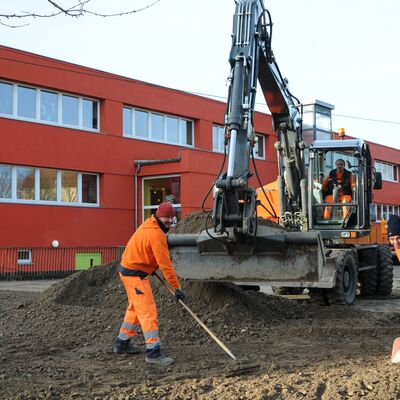 Drei Bauhofmitarbeiter füllen den Boden für den künftigen Standort der Modulbaukita mit Recyclingmaterial auf.
