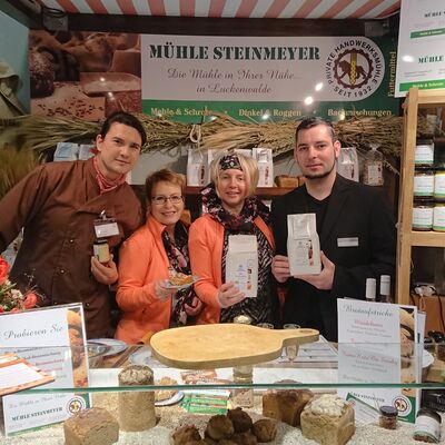Zwei Frauen und zwei Männer lächeln in die Kamera. Um sie herum ein Messestand für die Mühle Steinmeyer.