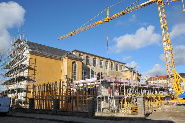 Bild vergr&ouml;&szlig;ern: Foto: Baustelle mit großem, gelben Gebäude. Daneben ein Kran.