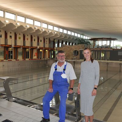 Foto: Eine Frau und ein Mann neben einem Hallenschwimmbecken.