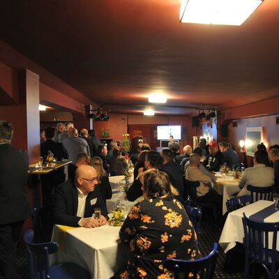 Foto: Ein Raum, in dem viele Menschen an Tischen sitzen.
