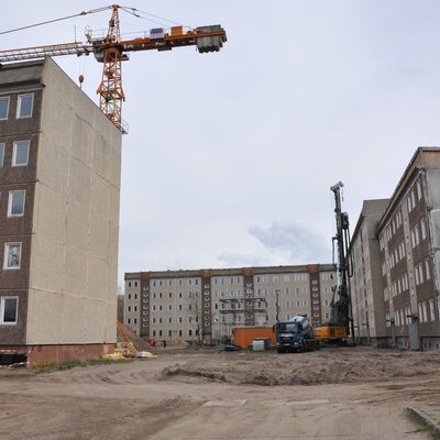 Foto: Eine Baustelle mit Plattenbauten und einem Kran.