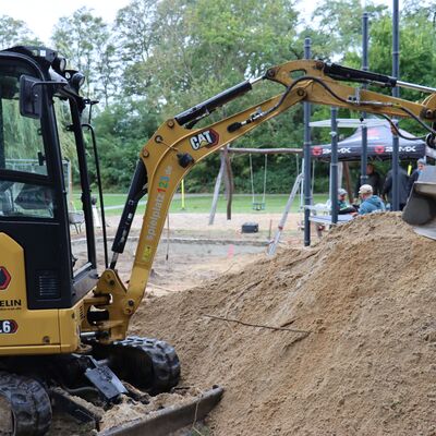 Bild vergr&ouml;&szlig;ern: Foto: Ein kleiner Bagger vor einem Spielplatz.