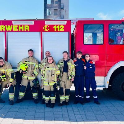 Feuerwehrleute stehen vor einem Einsatzfahrzeug.
