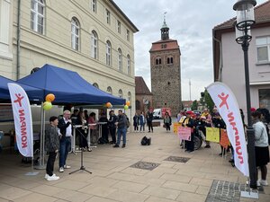 Bild vergr&ouml;&szlig;ern: Foto: Menschen und Stände, Plakate und Fahnen vor dem Luckenwalder Marktturm.