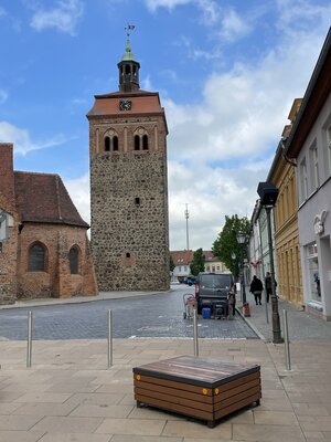 Bild vergr&ouml;&szlig;ern: Foto: Vier Edelstahlpfosten. Im Hintergrund der Luckenwalder Marktturm.