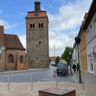 Foto: Vier Edelstahlpfosten. Im Hintergrund der Luckenwalder Marktturm.
