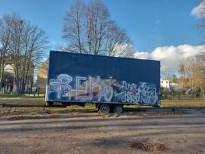 Bild vergr&ouml;&szlig;ern: Foto: Ein alter, beschmierter LKW-Anhänger vor Bäumen.