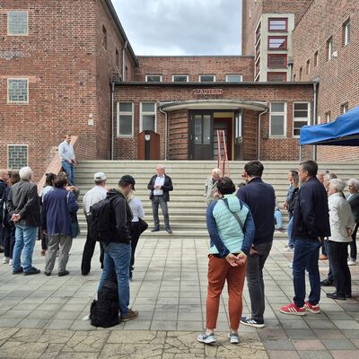 Foto: Zahlreiche Menschen vor einem großen Backsteingebäude.