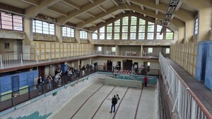 Bild vergr&ouml;&szlig;ern: Foto: Ein großes, leeres Hallenbad, in dem Menschen stehen.