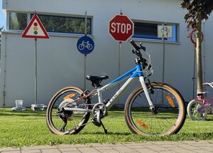 Bild vergr&ouml;&szlig;ern: Ein Fahrrad steht auf einer Wiese. Im Hintergrund sind verschiedene Verkehrszeichen aufgestellt.