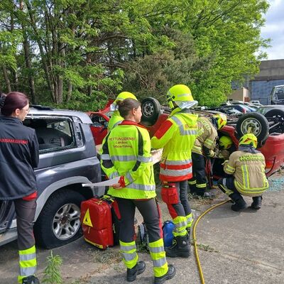 Bild vergr&ouml;&szlig;ern: Foto: Etliche Menschen, zum Teil in Einsatzkleidung, auf einem Parkplatz.