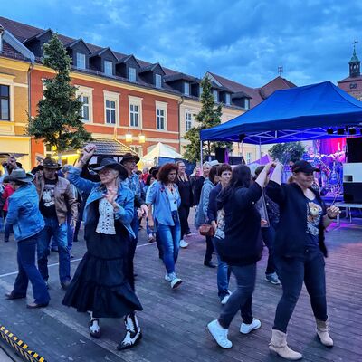 Bild vergr&ouml;&szlig;ern: Auf einer Holzbühne sind Tänzer.