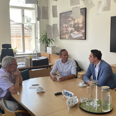 Foto: Drei Männer sitzen um einen Tisch herum.