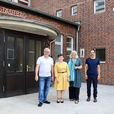 Vier Personen stehen vor einem alten Backsteingebäude.
