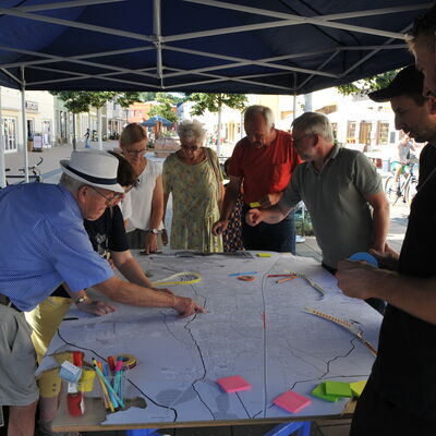 Bild vergr&ouml;&szlig;ern: Foto: Menschen beugen sich über einen Stadtplan.