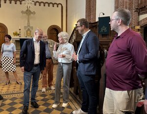 Bild vergr&ouml;&szlig;ern: Menschen stehen in einer Kirche.