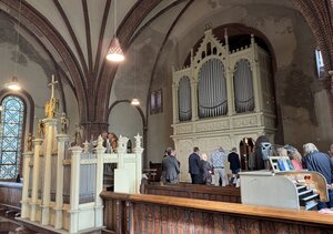 Bild vergr&ouml;&szlig;ern: Eine Orgel in einer alten Kirche, vor der Menschen stehen.