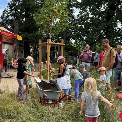 Bild vergr&ouml;&szlig;ern: Kinder stehen um einen Baum herum.