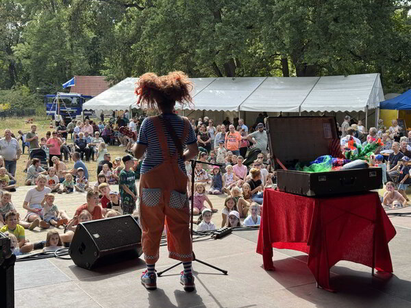 Bild vergr&ouml;&szlig;ern: Eine Clownin steht auf einer Bühne. Kinder schauen zu ihr.