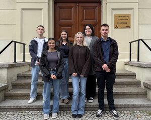 Bild vergr&ouml;&szlig;ern: Sechs junge Menschen stehen auf einer Treppe und lächeln in die Kamera.