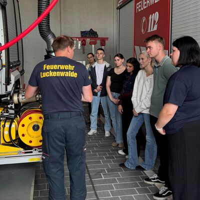 Bild vergr&ouml;&szlig;ern: Personen stehen an einem Feuerwehrfahrzeug und begutachten die Technik.