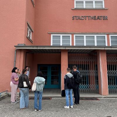 Bild vergr&ouml;&szlig;ern: Menschen stehen vor dem Eingang eines Theaters.