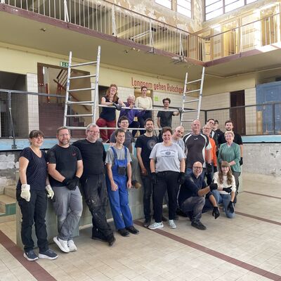 Bild vergr&ouml;&szlig;ern: Foto: Eine große Gruppe Menschen in einem leeren Schwimmbecken.