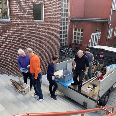 Bild vergr&ouml;&szlig;ern: Foto: Menschen auf einer Treppe. Daneben steht ein Transporter.