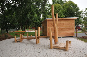 Bild vergr&ouml;&szlig;ern: Foto: Hölzerne Spielgeräte und ein Schuppen.