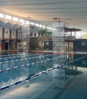 Bild vergr&ouml;&szlig;ern: Foto: Zwei Gerüste stehen neben einem Schwimmbecken in einer Halle.