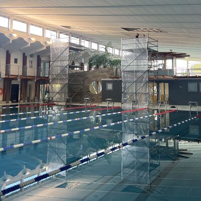 Foto: Zwei Gerüste stehen neben einem Schwimmbecken in einer Halle.