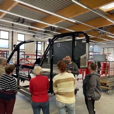 Foto: Menschen stehen vor einem schwarzen Metallgehäuse in einer großen Halle.